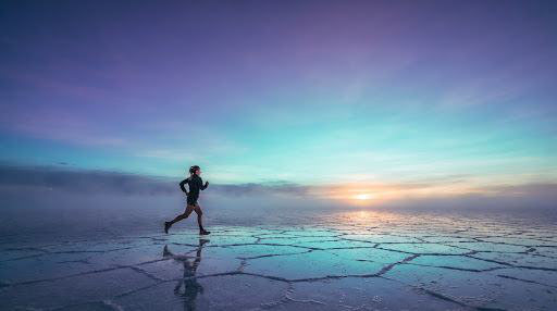 Runner on a reflective landscape at sunrise