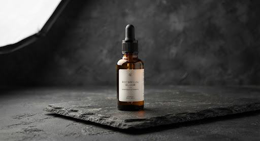 Amber dropper bottle on dark slate with soft directional studio light.